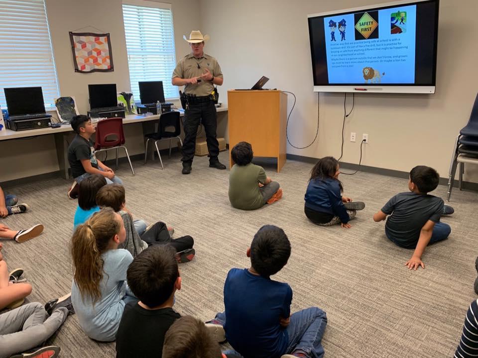 Children in classroom watching officers speak 