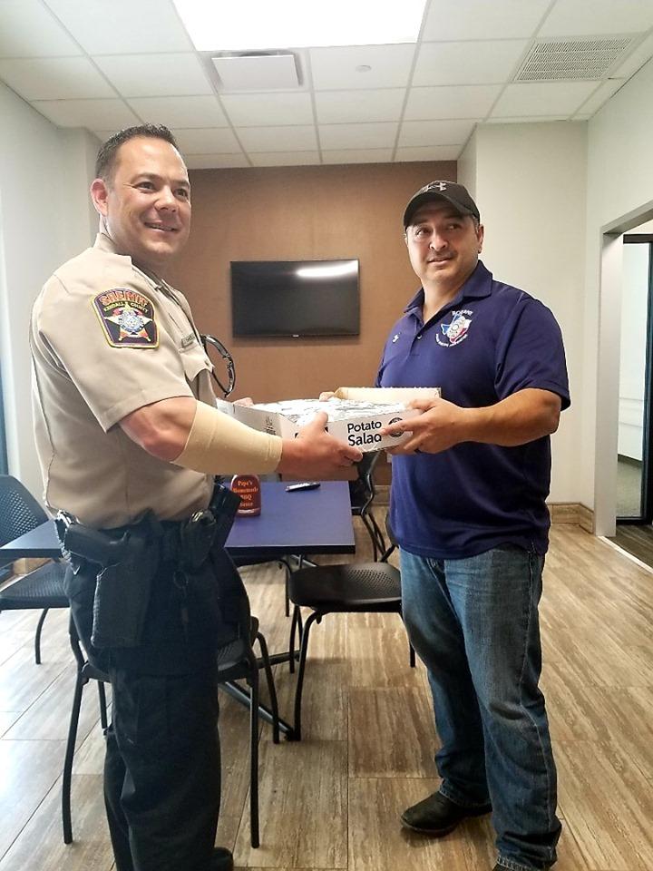 Officer receiving BBQ from Local Business Owner 