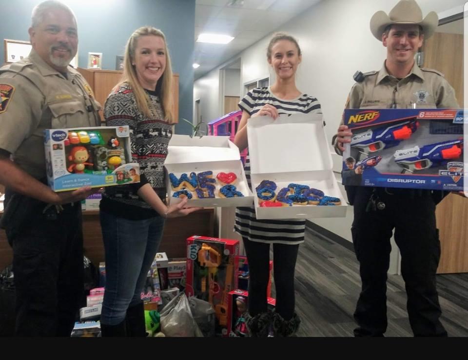 Officers with two ladies from toy drive with toys and donuts 